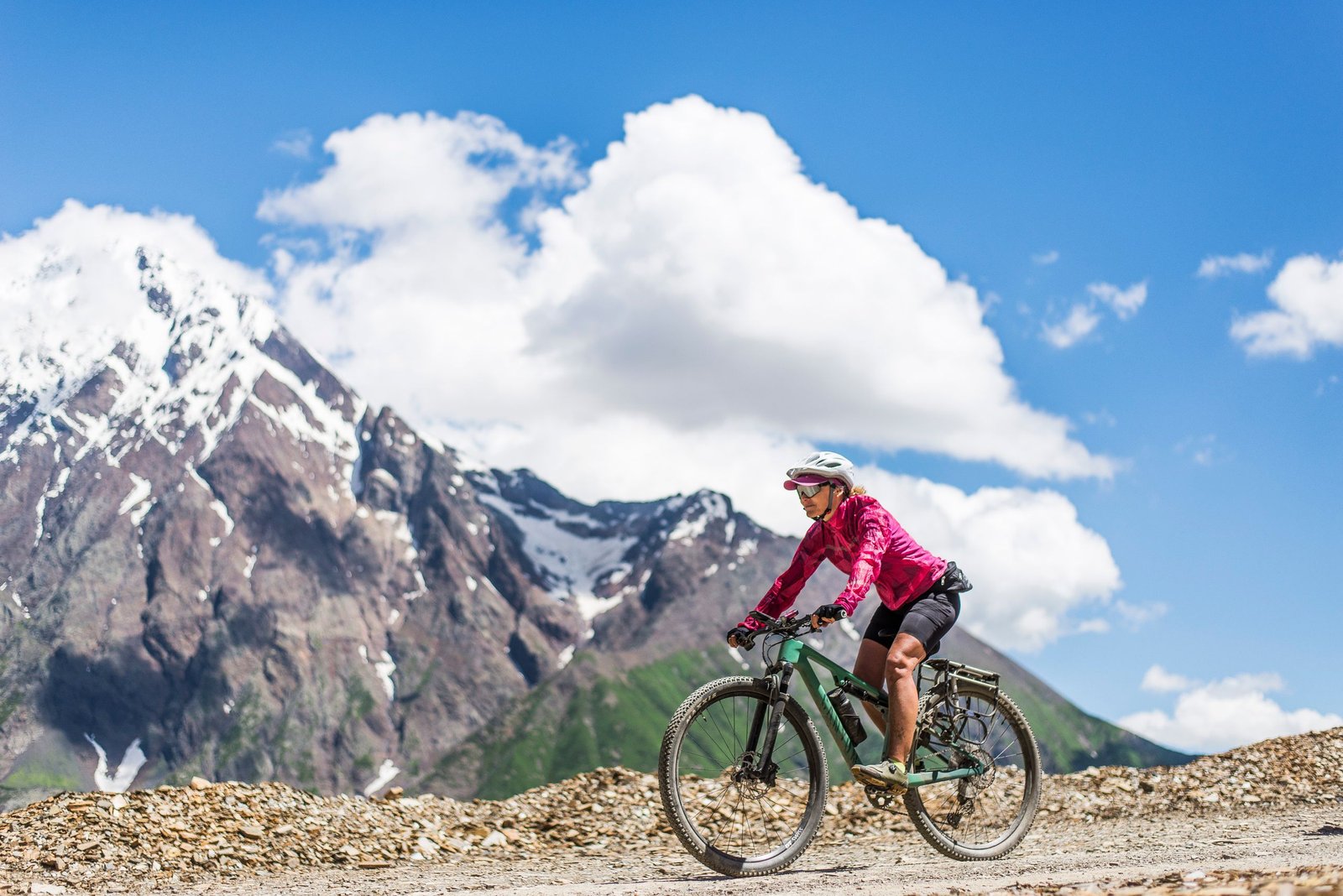A cyclist rides through a mountainous trail on a sunny summer day, showcasing adventure and freedom.