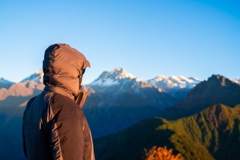 A hiker in warm clothing gazing at the beautiful mountain landscape in Nepal.