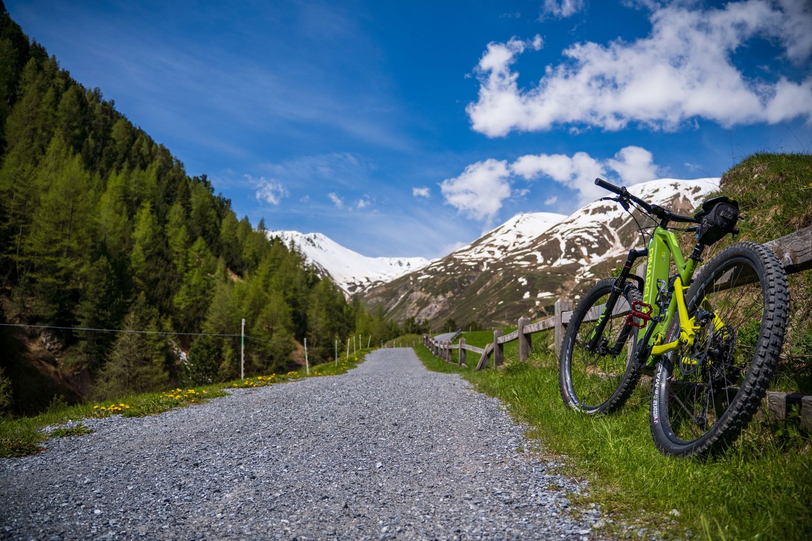 A vibrant bicycle rests on a gravel road through the snowcapped mountains of Livigno, Italy.